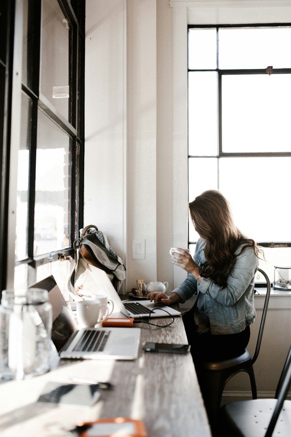 Femme à table, tasse en main – télétravail bien assuré