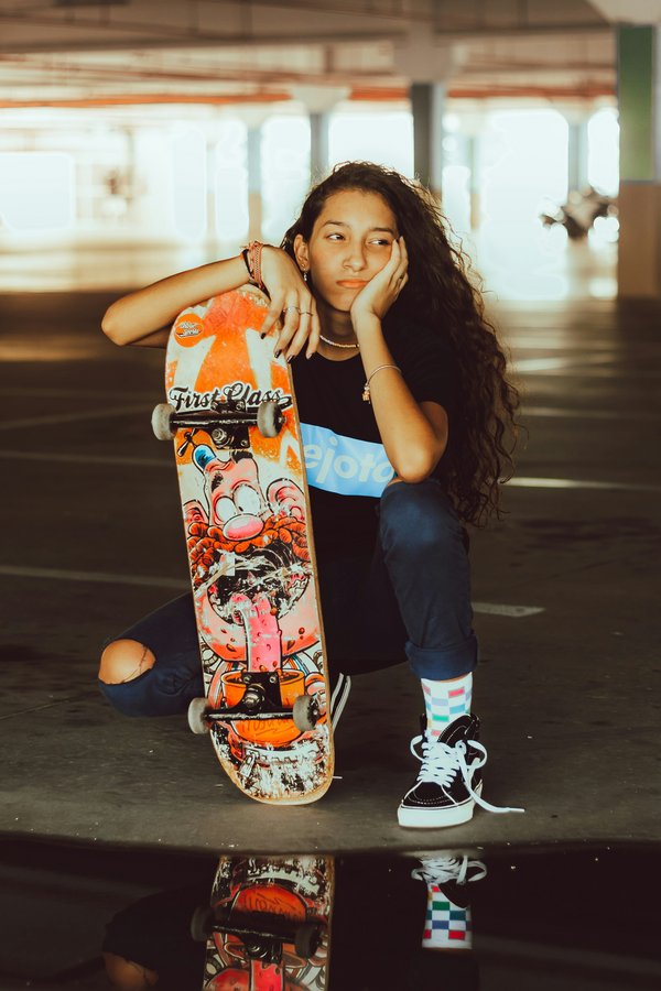 Jeune femme agenouillée au sol avec skateboard – assurance loisirs actifs