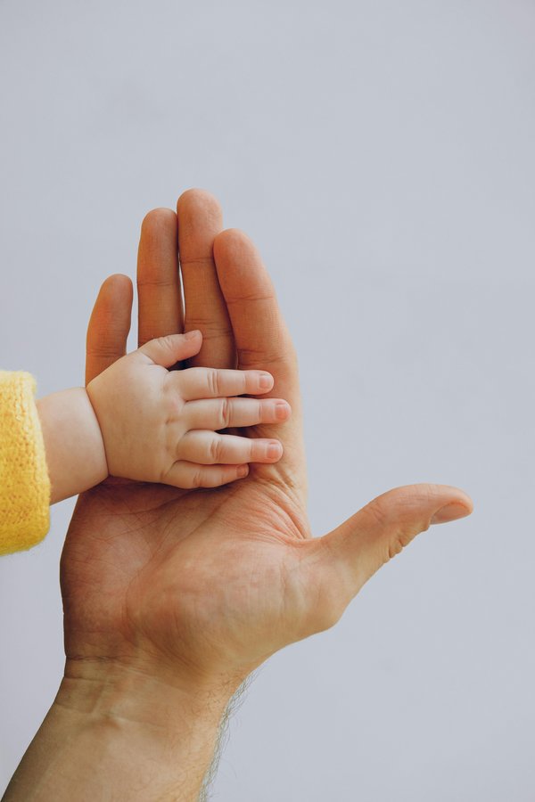 Mains d’un père et de son fils symbolisant la planification financière pour l’avenir familial 