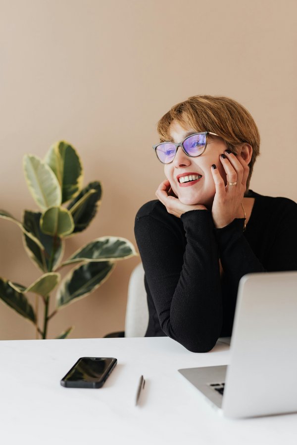 Femme rêveuse avec téléphone et ordinateur – assurance et projets d’avenir