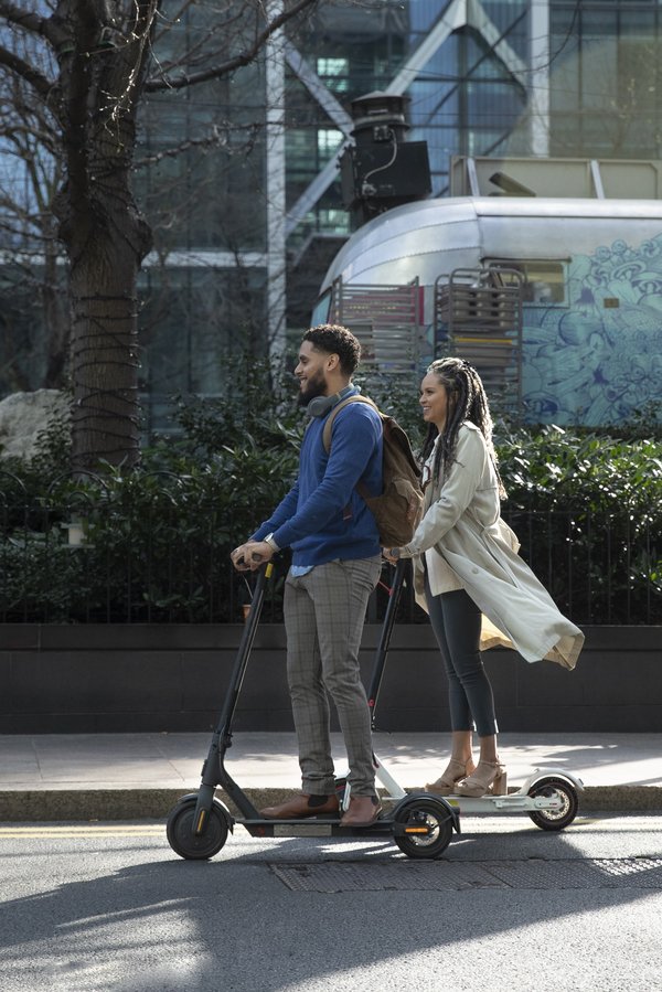 Jeunes cosmopolites roulant sur piste cyclable avec trottinette électrique – mobilité moderne assurée