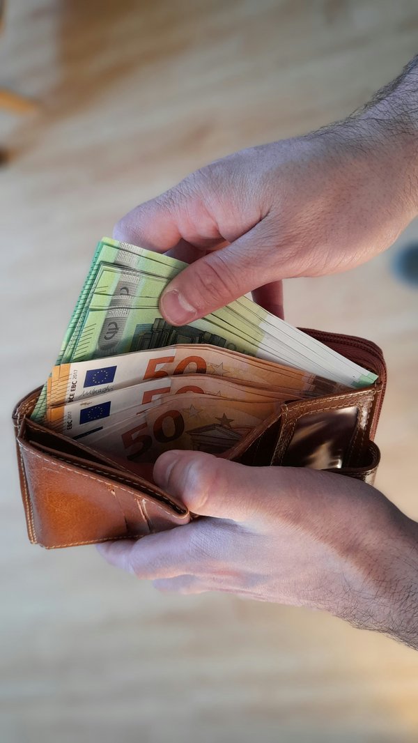 Main glissant de l’argent dans une poche, illustrant l’assurance pension comme solution d’avenir au Luxembourg