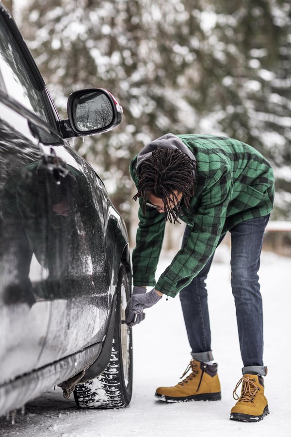Jeune homme testant les pneus et équipements hivernaux avant départ à l’étranger – sécurité routière