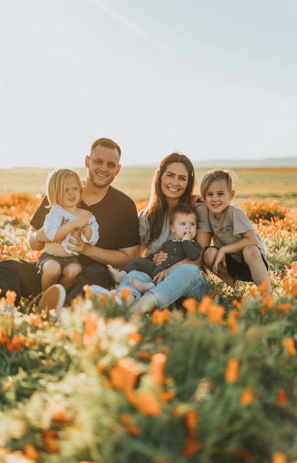 Famille avec trois enfants assise dans un pré fleuri – bons moments assurés ensemble