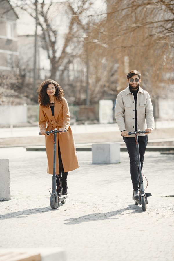 Homme et femme roulant en e-scooter – mobilité urbaine assurée