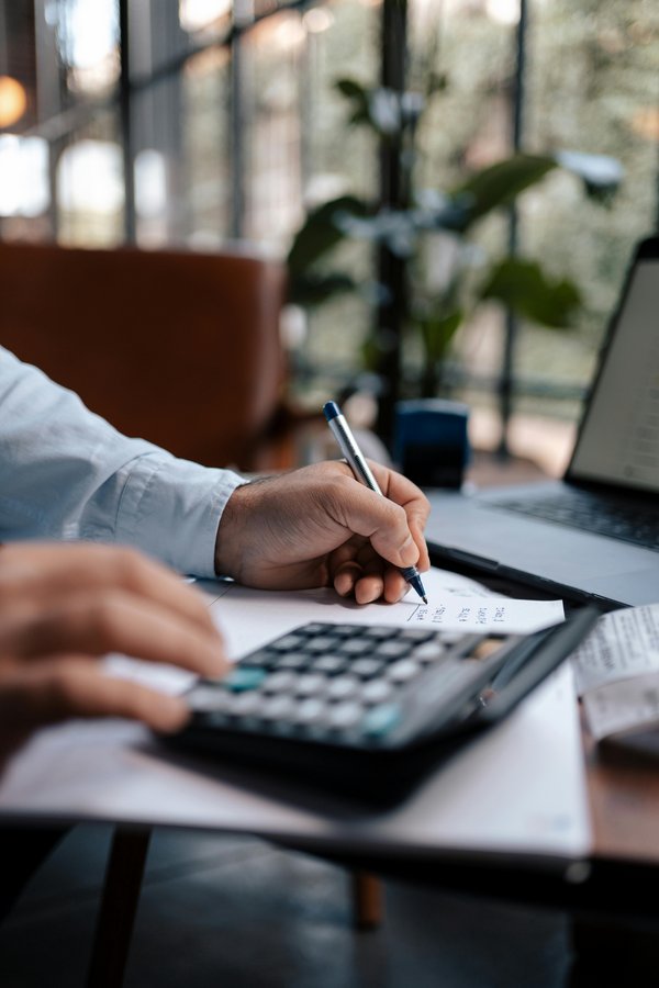 Calculatrice et main qui écrit – gestion budgétaire assurée